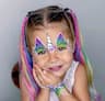 Girl at a birthday party in Dubai with kanekalon braided hair, unicorn face painting and hand painting design, and kids nail polish