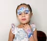 A girl with Frozen Elsa face painting and hand painting design at a community event in Dubai